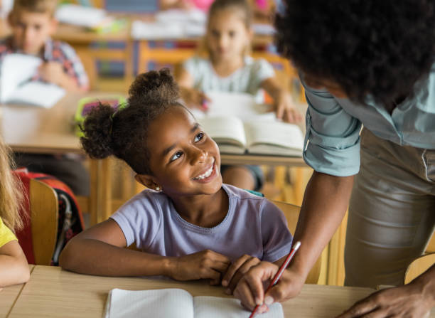 istock Happy black girl talking to her teacher during a class at elementary school. 1064029228