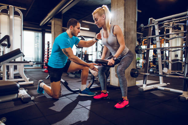 istock Young woman lifting weights with help of personal trainer 1064040484