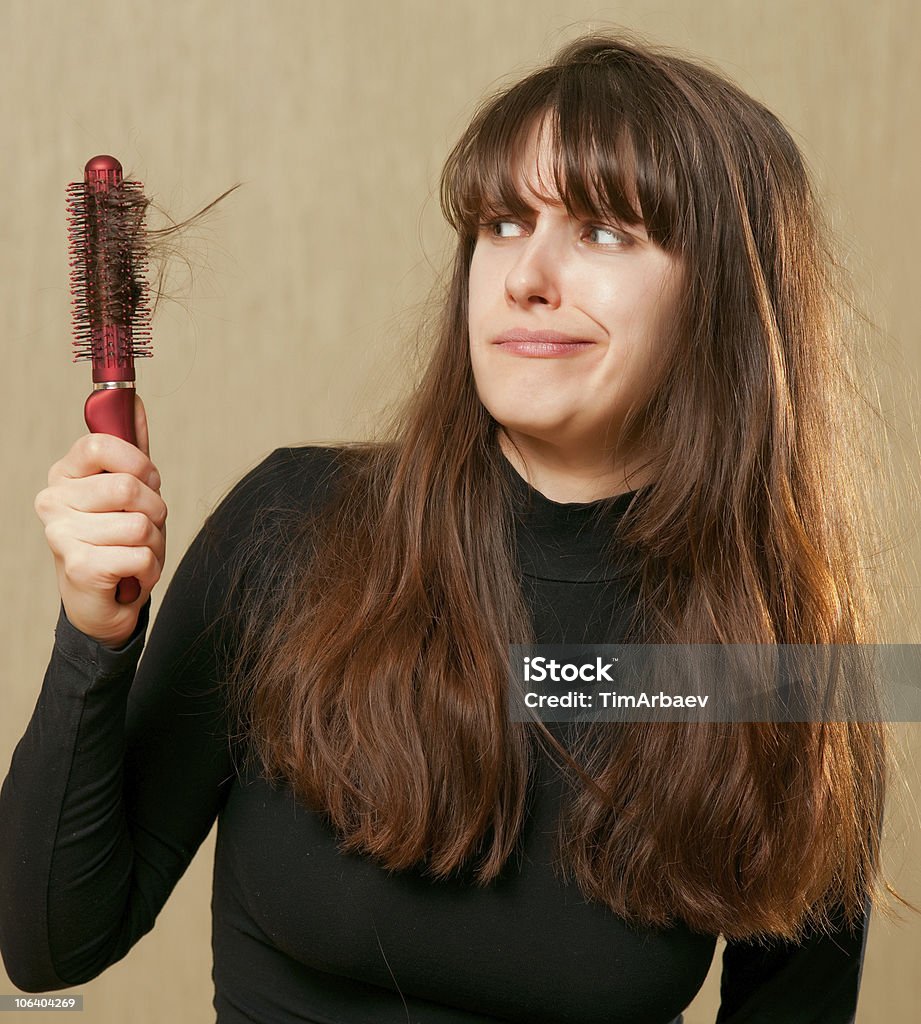 Confused woman with tangled hair Confused woman with tangled hair holds a hairbrush in the hand Adult Stock Photo