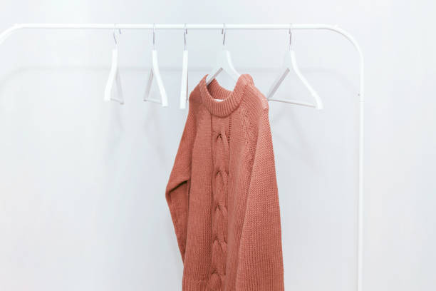istock One orange pastel knit warm sweater on hanger and many empty hangers. 1064043500