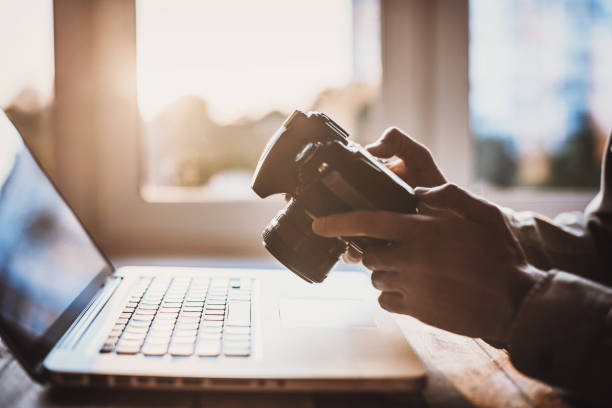 istock Photographer working with laptop and DSLR camera 1064057022