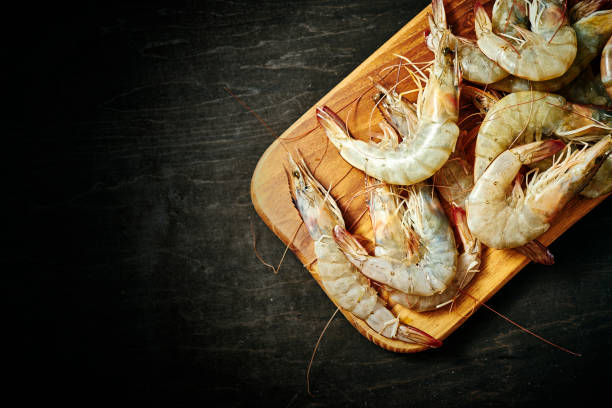 istock fresh delicious raw tiger prawns on a wooden board on a black table 1064058368