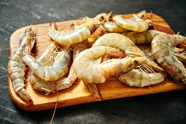 istock fresh delicious raw tiger prawns on a wooden board on a black table 1064058464