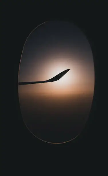 silhouette view of airplane wing see through window at sunset time.travel concept