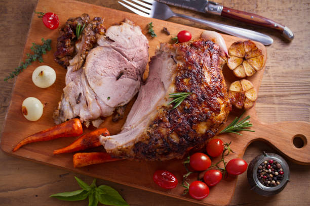 istock Baked ham with vegetables, rosemary and thyme on chopping board 1064071028