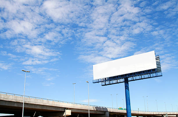 A large blank billboard near a main road on a cloudy day stock photo