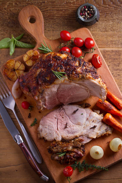 istock Baked ham with vegetables, rosemary and thyme on chopping board 1064075660