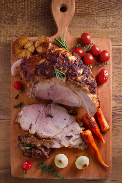 istock Baked ham with vegetables, rosemary and thyme on chopping board 1064079274