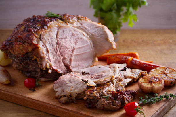 istock Baked ham with vegetables, rosemary and thyme on chopping board 1064079470