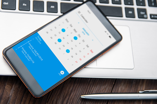 Muesca de la bruja de smartphone se encuentra en el escritorio con aplicación de calendario que recordar sobre las facturas a pagar photo