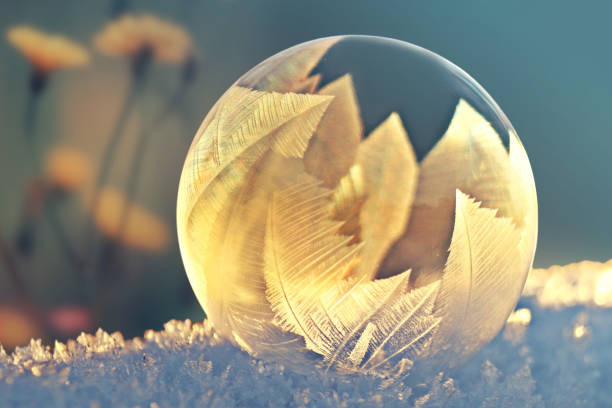 Frozen soap bubble ball on snow in sunset, crystal formation, winter background with copy space