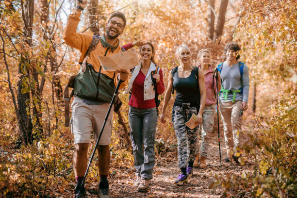 istock Man holding map and showing other hikers right way while walking in woods. 1064081844