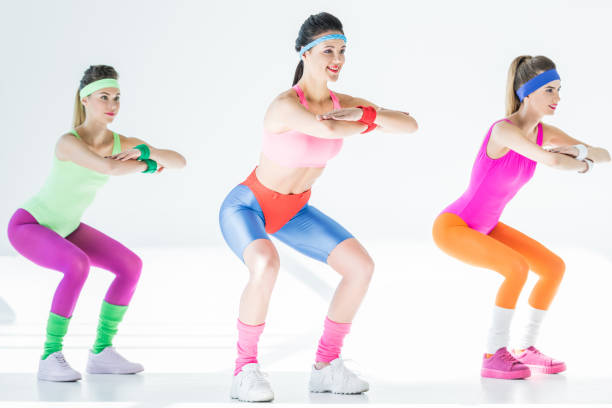 full length view of sporty smiling girls doing squat on grey full length view of sporty smiling girls doing squat on grey 80s aerobics stock pictures, royalty-free photos & images