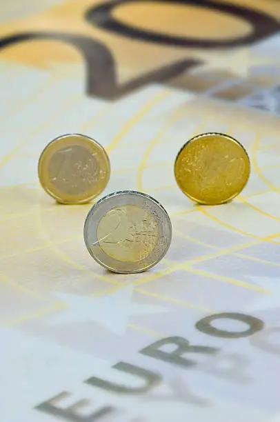 Euro- and Cent-coins rolling over a Euro-banknote