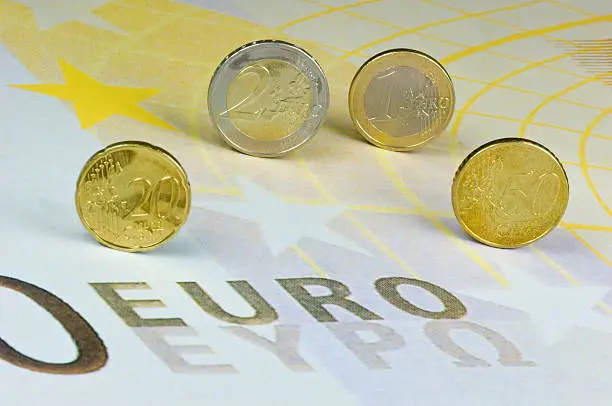 Euro-coins rolling over a Euro-banknote