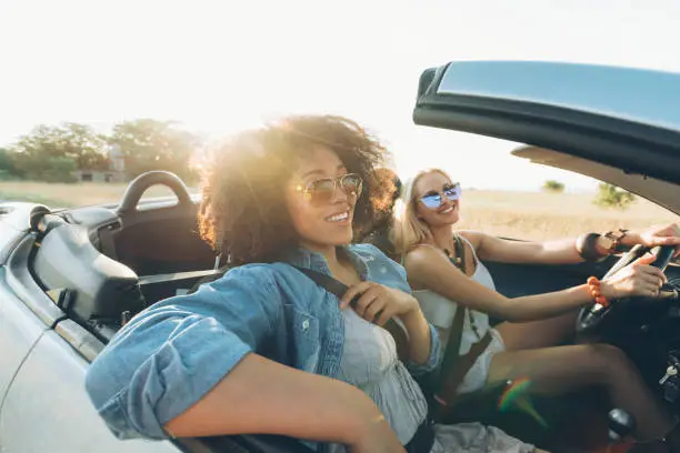 Young women on road trip with cabriolet, having fun.