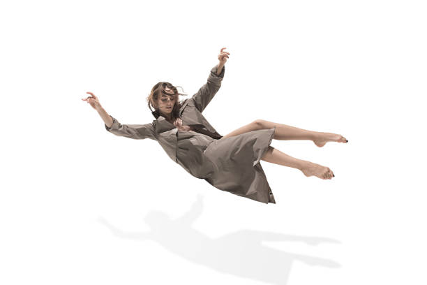 Beautiful slim young female modern jazz contemporary style ballet dancer Beautiful slim young female modern jazz contemporary style ballet dancer in silhouette wearing beige long cloak flying isolated on a white studio background floating woman stock pictures, royalty-free photos & images