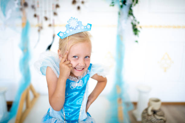 young happy kid Prepare for the new year party, the snow queen or the Snow Maiden princess. Beautiful girl with a cardboard caron. Blonde holding a decoration on a wooden stick. Original accessories for photo shoots princess stock pictures, royalty-free photos & images