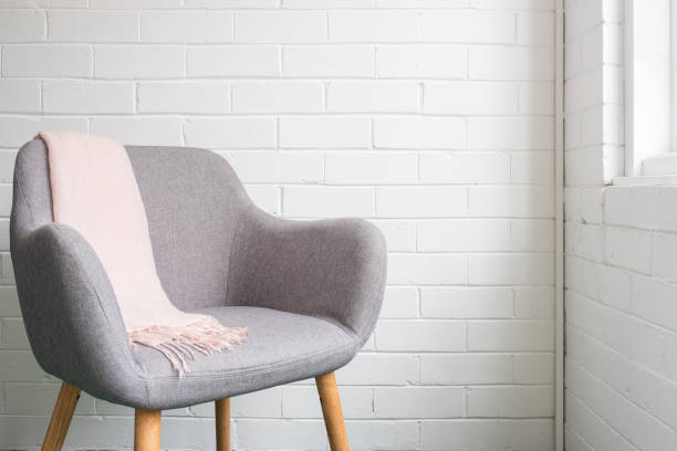 istock Grey chair with soft pink throw against white wall 1064095232