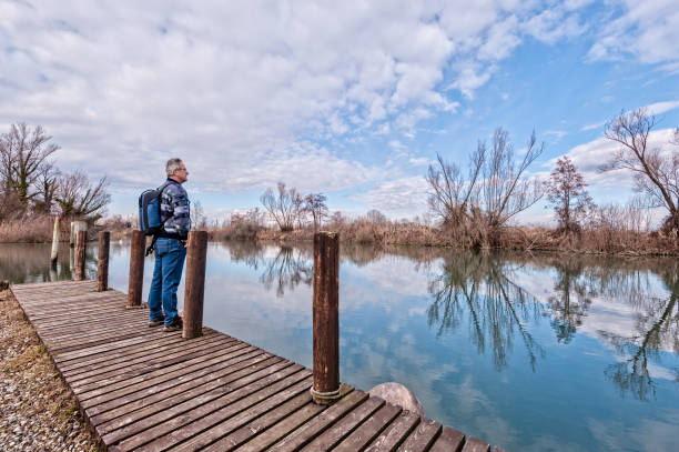 istock Hiker with backpack over wood pier on shore of river. 1064098396