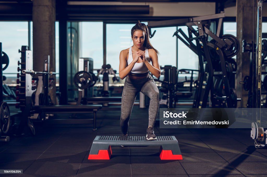 Young woman exercising on step aerobics equipment at gym Gym Stock Photo