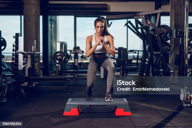 Young Woman Exercising On Step Aerobics Equipment At Gym Stock Photo - Download Image Now