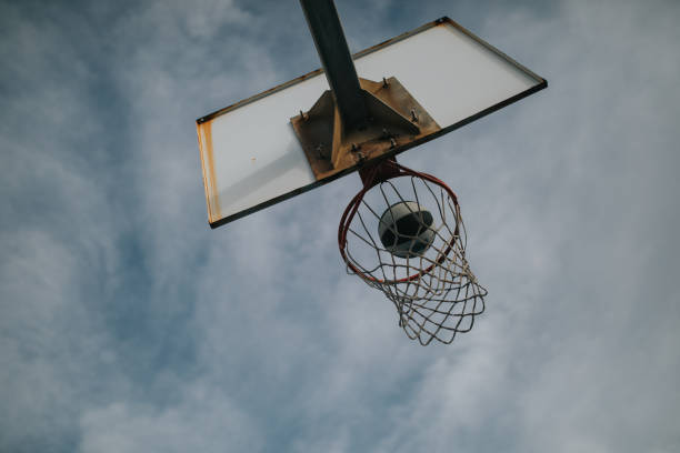 istock Basket ball entering into a basketball ring with blue sky background. 1064115392