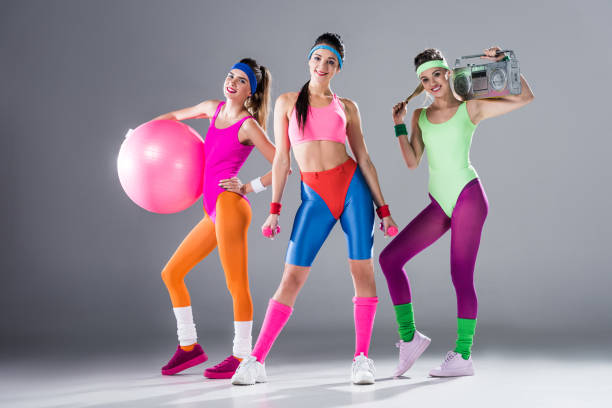 beautiful sporty girls with sports equipment and tape recorder smiling at camera on grey beautiful sporty girls with sports equipment and tape recorder smiling at camera on grey 80s aerobics stock pictures, royalty-free photos & images