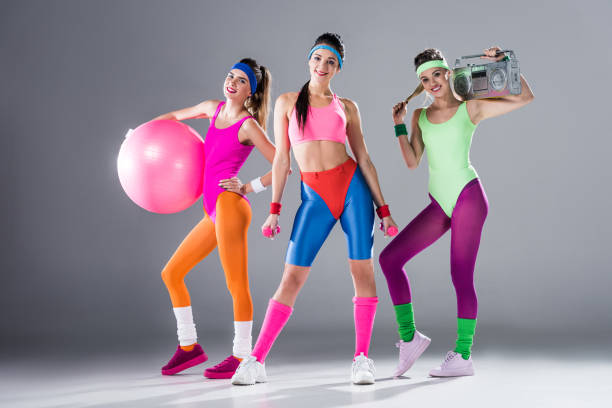 beautiful sporty girls with sports equipment and tape recorder smiling at camera on grey - aerobics imagens e fotografias de stock