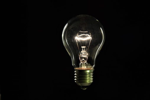 Idea concept with classic light bulb glowing in the dark. This file is cleaned and retouched.