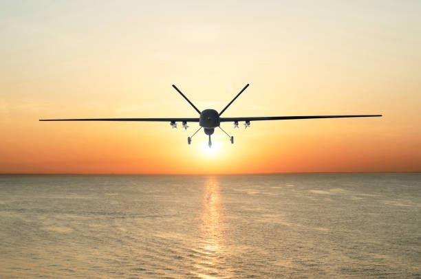 Unmanned military drone patrols the territory at sunset, flying above water surface. The view is straight ahead. Unmanned military drone patrols the territory at sunset, flying above water surface. The view is straight ahead unmanned aerial vehicle stock pictures, royalty-free photos & images