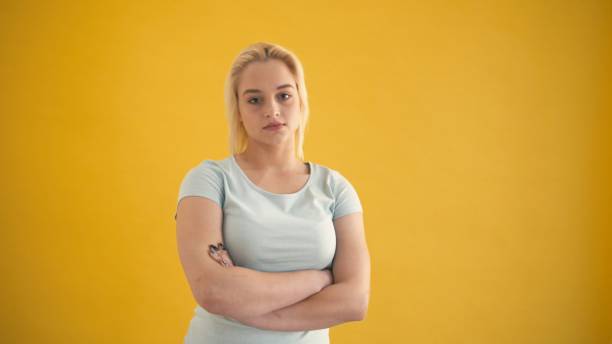 istock Young blond caucasian plus size model posing with crossing hands at yellow background 1064128808