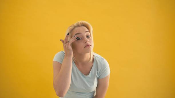 istock Plus size model touch her face make up and look at camera like in mirror at yellow background 1064130456