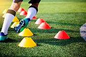 istock Soccer player Jogging and jump between cone markers on green artificial turf for soccer training. 1064136992