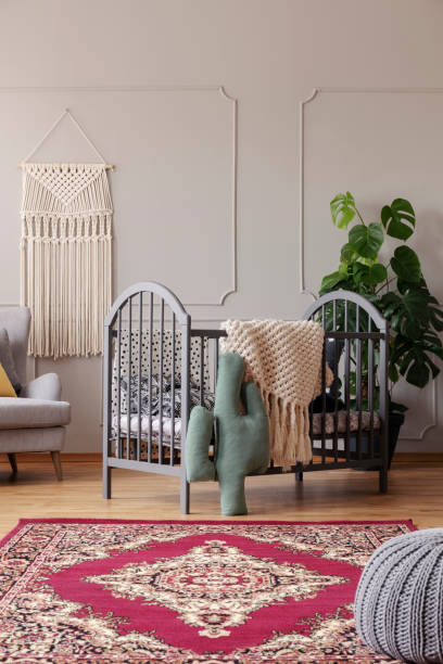 istock Patterned carpet in front of grey cradle with cactus pillow in baby's bedroom interior. Real photo 1064137062