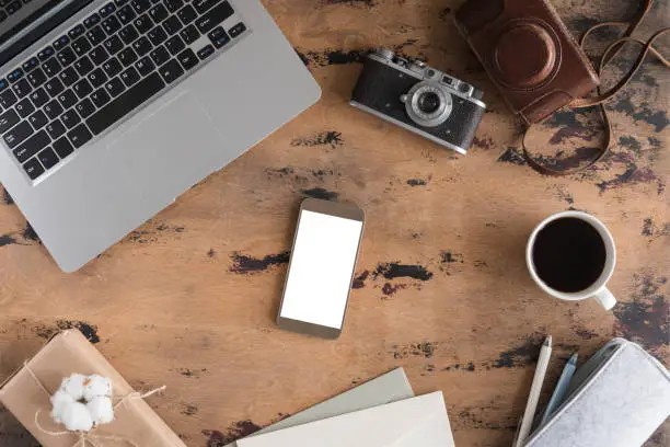 Photo of Vintage office desk with retro photo Camera, laptop, cup of tea and supplies and mobile phone on wooden table background. Top view with copy space, flat lay