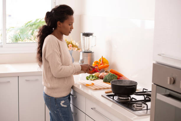 istock Woman peeling carrots for soup preparation at the kitchen. 1064138214
