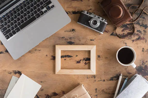 Photo of Vintage office desk with retro photo Camera, laptop, cup of tea and supplies on wooden table background. Top view with copy space, flat lay