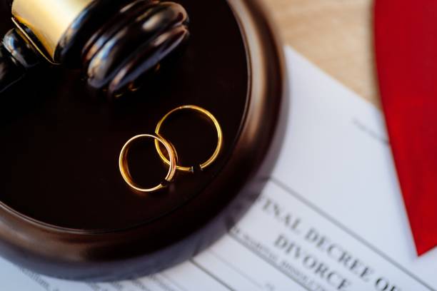 istock Two broken golden wedding rings on judge gavel. 1064149236