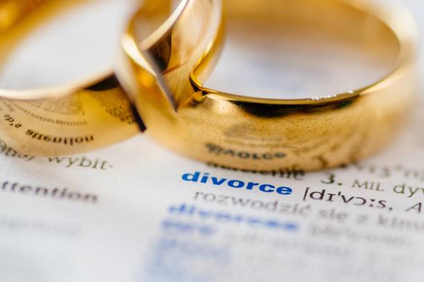 istock Two broken wedding rings on divorce word in dictionary. 1064149292