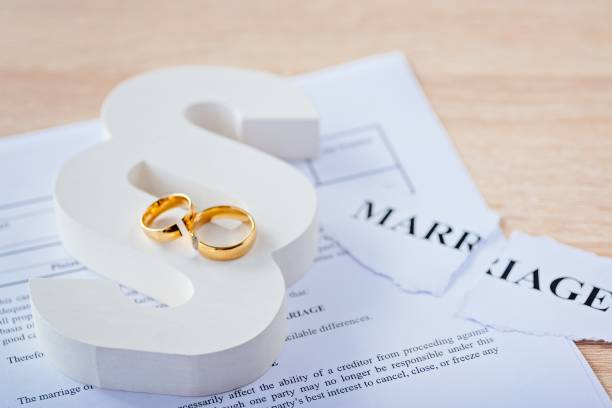 istock Two broken wedding rings on wooden paragraph. 1064149470