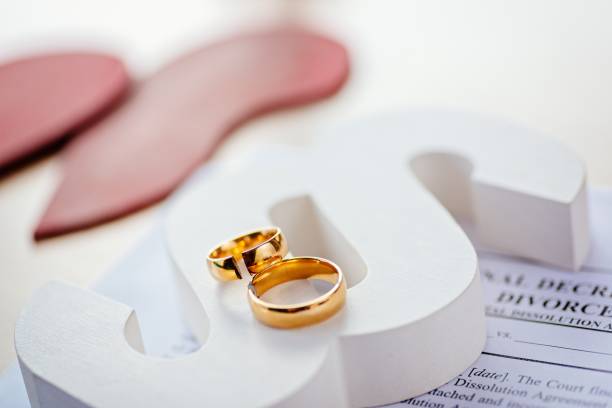 istock Two broken wedding rings on wooden paragraph. 1064149474