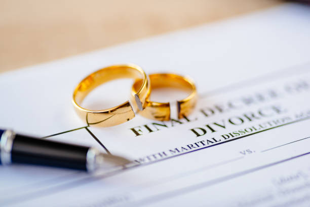 istock Broken wedding rings on divorce decree. 1064149560