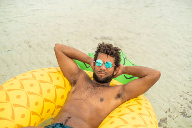 vista aerea dell'uomo con materasso gonfiabile a forma di ananas, sorridente. - men swimming trunks beach racing briefs foto e immagini stock