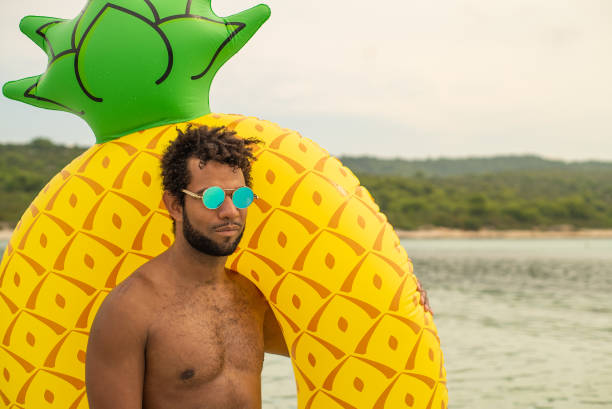 vista aerea dell'uomo con materasso gonfiabile a forma di ananas, sorridente. - men swimming trunks beach racing briefs foto e immagini stock