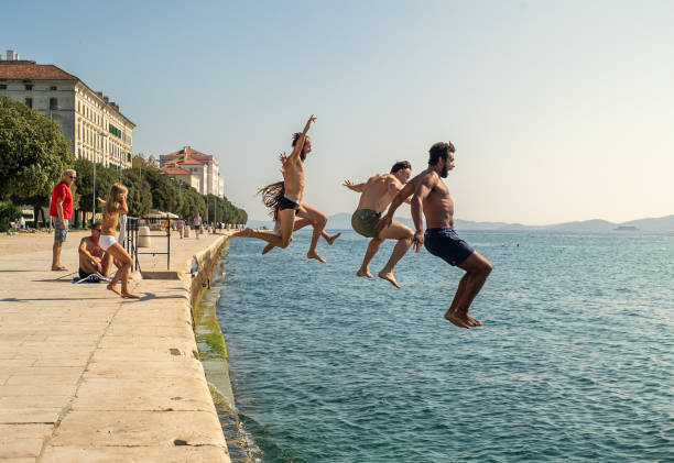 Group of courageous people jumping into harbour sea of Zadar, Croatia. stock photo
