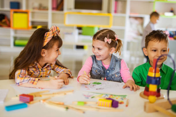 istock Happy kids talking while drawing in preschool. 1064160860