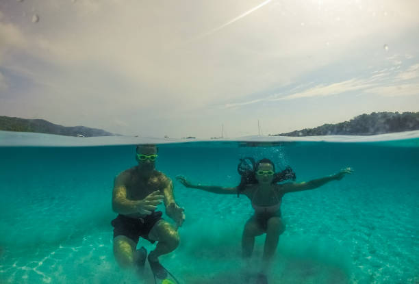 istock Underwater split screen view of couple diving apnea. 1064161302