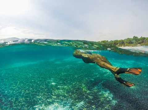 Underwater split screen view of man diving apnea.