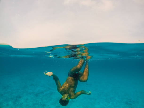 Underwater split screen view of man diving apnea.
